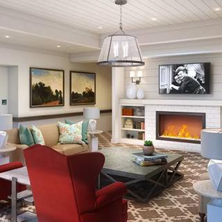 A modern living room with a fireplace, artwork on the walls, and comfortable seating including a red armchair.