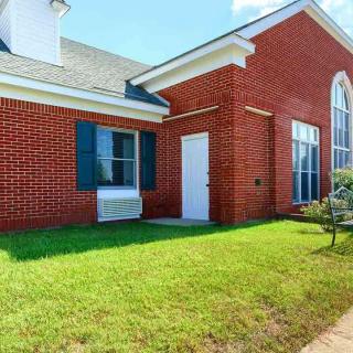 A brick building with large windows, a white door, and a neatly maintained lawn.