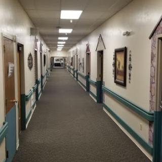 A view of a well-lit hallway with doors on both sides and decorative elements on the walls.