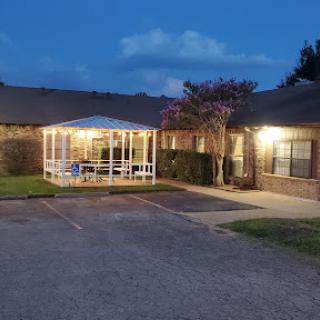 A serene evening view of a building with a gazebo, illuminated by soft lights.