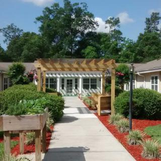 A beautifully landscaped garden pathway leading to a building entrance with a wooden pergola.