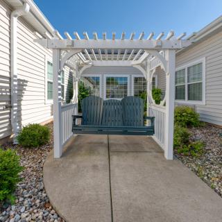 A charming outdoor space featuring a pergola with a swing in a neatly landscaped garden.