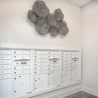 A modern interior featuring a set of white mailboxes with artistic wall decor above.