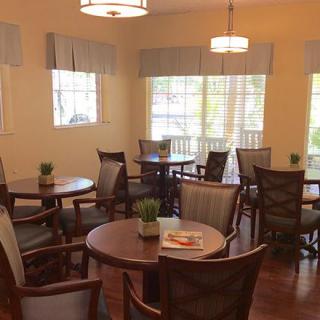A cozy dining area with round tables and chairs, warmly lit by ceiling lights.