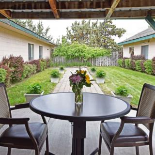 A cozy patio with a table and two chairs overlooks a lush garden.