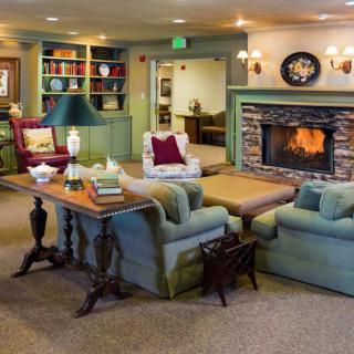 A cozy living room with a warm fireplace, comfortable seating, and bookshelves.