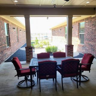 Cozy patio with red cushioned chairs under a covered area.