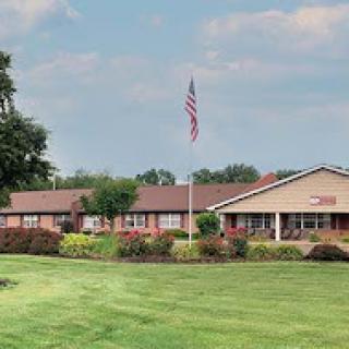 A well-maintained building with an American flag in front, surrounded by lush greenery.