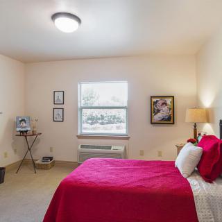 A cozy bedroom with red bedding and soft lighting.