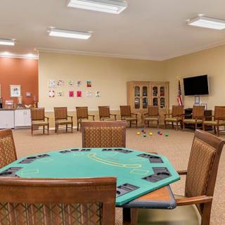 A spacious recreation room with a poker table and chairs, a television, and a cabinet.