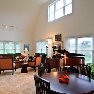 Spacious living room with a grand piano and abundant natural light.