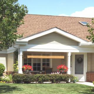 A charming suburban house with a well-kept front yard and flowers on the porch.