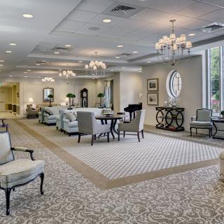 A spacious and elegantly designed lobby with comfortable seating, decorative mirrors, and chandeliers.