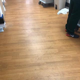 A wooden floor hallway with a person standing, visible from the waist down.