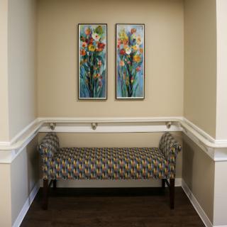 A cozy corner featuring a patterned bench and vibrant floral artwork.