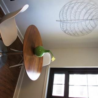 A modern dining area with a round wooden table, white chairs, and a vase with a flower.