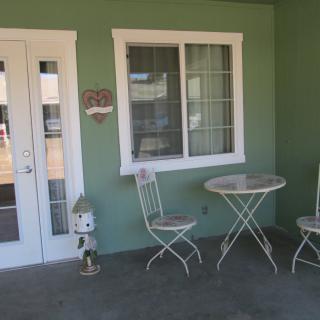 A cozy patio with a small table and two chairs against a green wall.