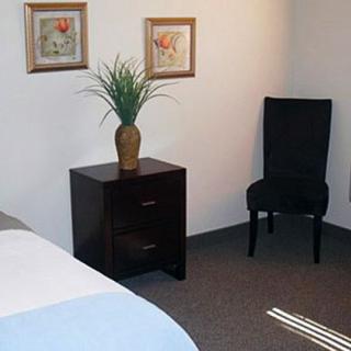 A cozy bedroom with a nightstand, chair, and decorative elements.