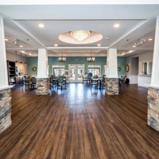 A spacious hall with wooden flooring, columns, and decorative lighting.