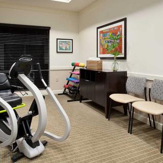 A small exercise room with gym equipment and colorful artwork on the walls.