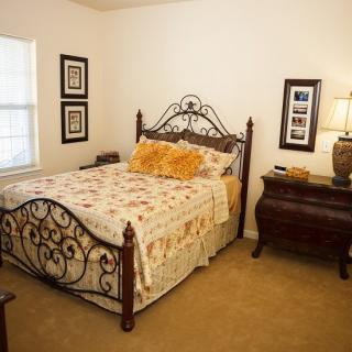 A cozy bedroom with an ornate iron bed frame, floral bedding, and classic wooden furniture.