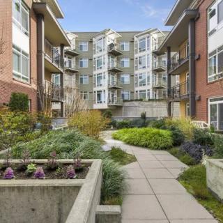 A modern apartment complex featuring a landscaped outdoor courtyard with a paved pathway.