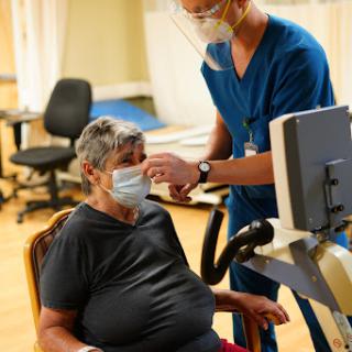 A healthcare professional assisting an elderly patient during a medical assessment.