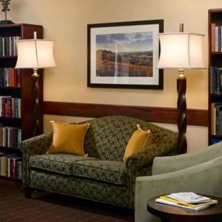 Cozy living room with a patterned sofa, standing lamps, and bookshelves.