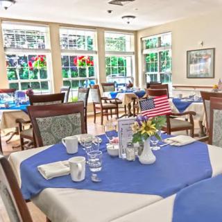 A bright dining room with tables elegantly set and large windows allowing natural light.