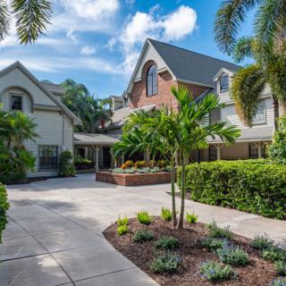 A beautiful residential house with a landscaped driveway and lush greenery under a blue sky.