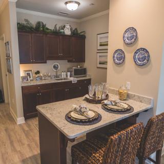 A cozy kitchen with a small dining area featuring bar stools and a countertop, adorned with decorative plates and set for two.