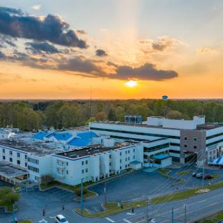 A beautiful sunset behind a hospital building, showcasing the contrast between modern architecture and the natural sky.