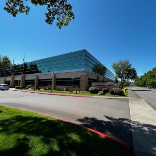 A modern office building surrounded by trees and a clear blue sky.