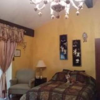 A cozy bedroom with yellow walls, a chandelier, and decorative elements.