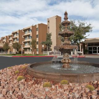 A scenic view of a hotel with a decorative fountain in the foreground.