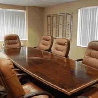 A conference room with a large wooden table and leather chairs.