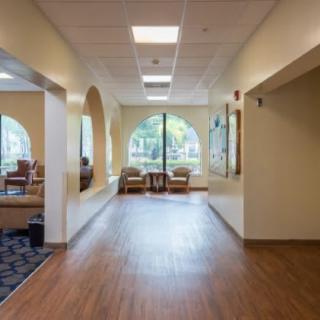 A hallway with a seating area and large windows.