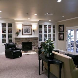 A cozy living room featuring a fireplace, armchairs, and built-in bookshelves.