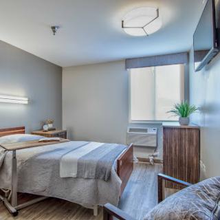 A modern hospital patient room featuring a bed, bedside table, and large window.