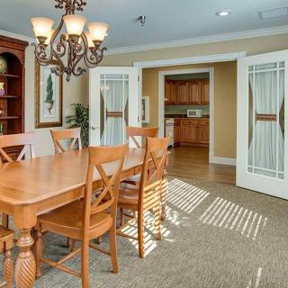 A cozy dining room with a wooden table and chairs, illuminated by an elegant chandelier, featuring sliding doors that lead to the kitchen.
