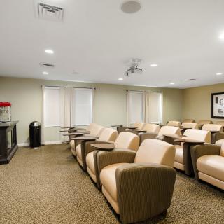An indoor theater room with arranged seating and a projector screen.