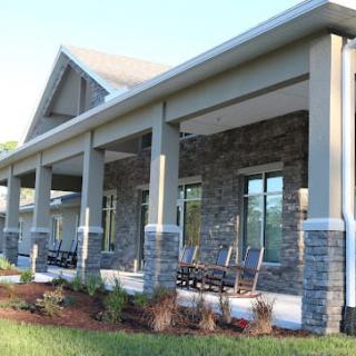 A modern house with a stone facade and spacious porch area.