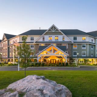 A charming hotel building surrounded by a landscaped lawn in the evening light.