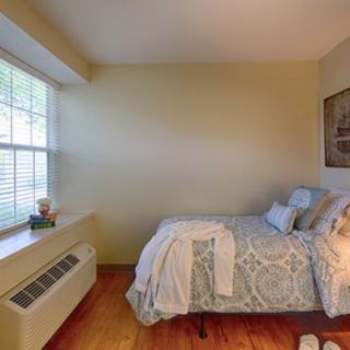 A cozy bedroom with a bed near a large window, allowing natural light to fill the room.