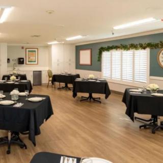 A neatly arranged dining area with tables covered in black tablecloths and simple decor.