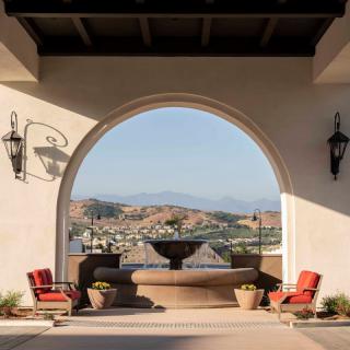 A luxurious patio with an archway frames a stunning view of the mountains.