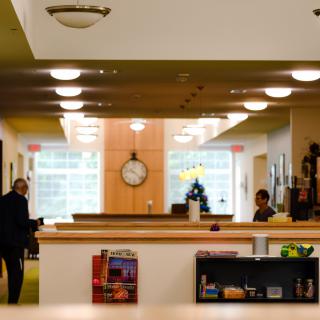 A modern library interior with bookshelves, a clock, and people studying.