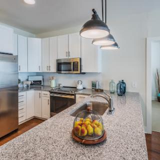 A modern kitchen featuring a sleek countertop, stainless steel appliances, and stylish pendant lighting.