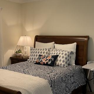 A cozy bedroom with a neatly made bed adorned with patterned pillows and a bedside lamp.