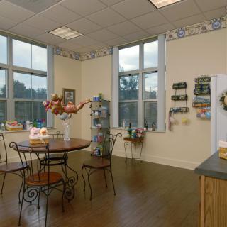 A cozy kitchen interior with a dining area featuring a round table and chairs, decorated with wall shelves and large windows.